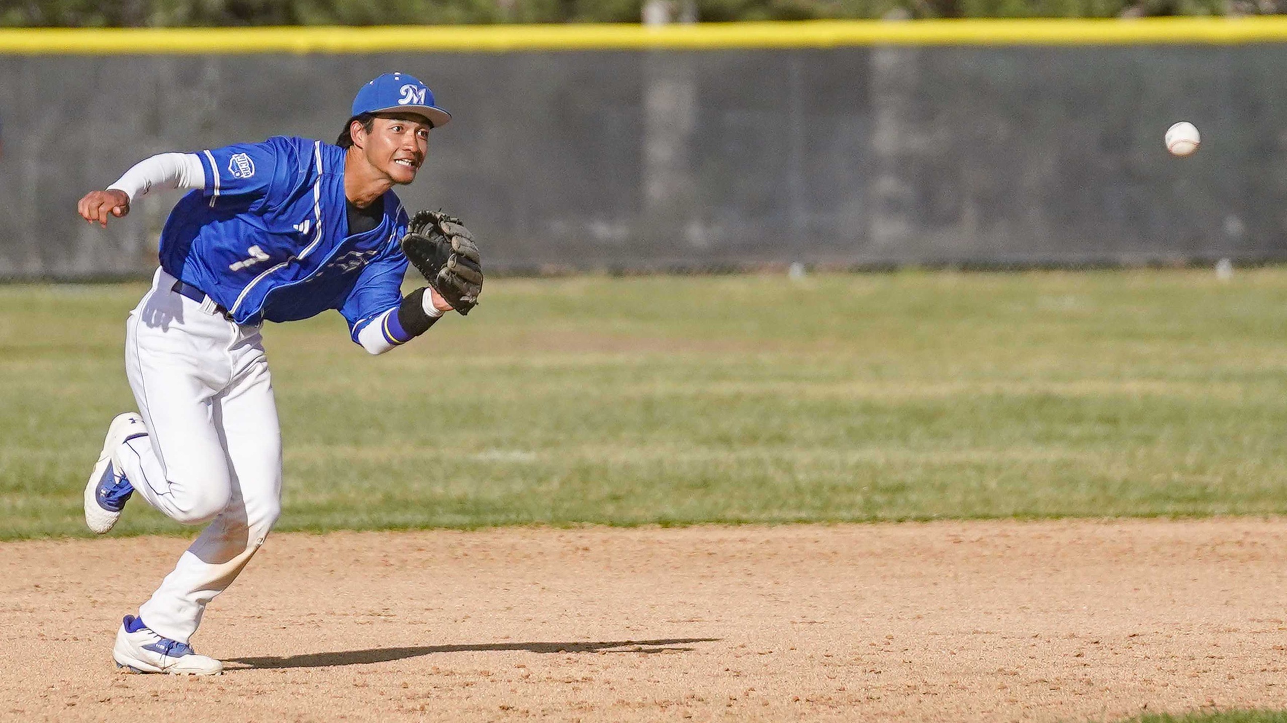 College baseball player fielding the ball.