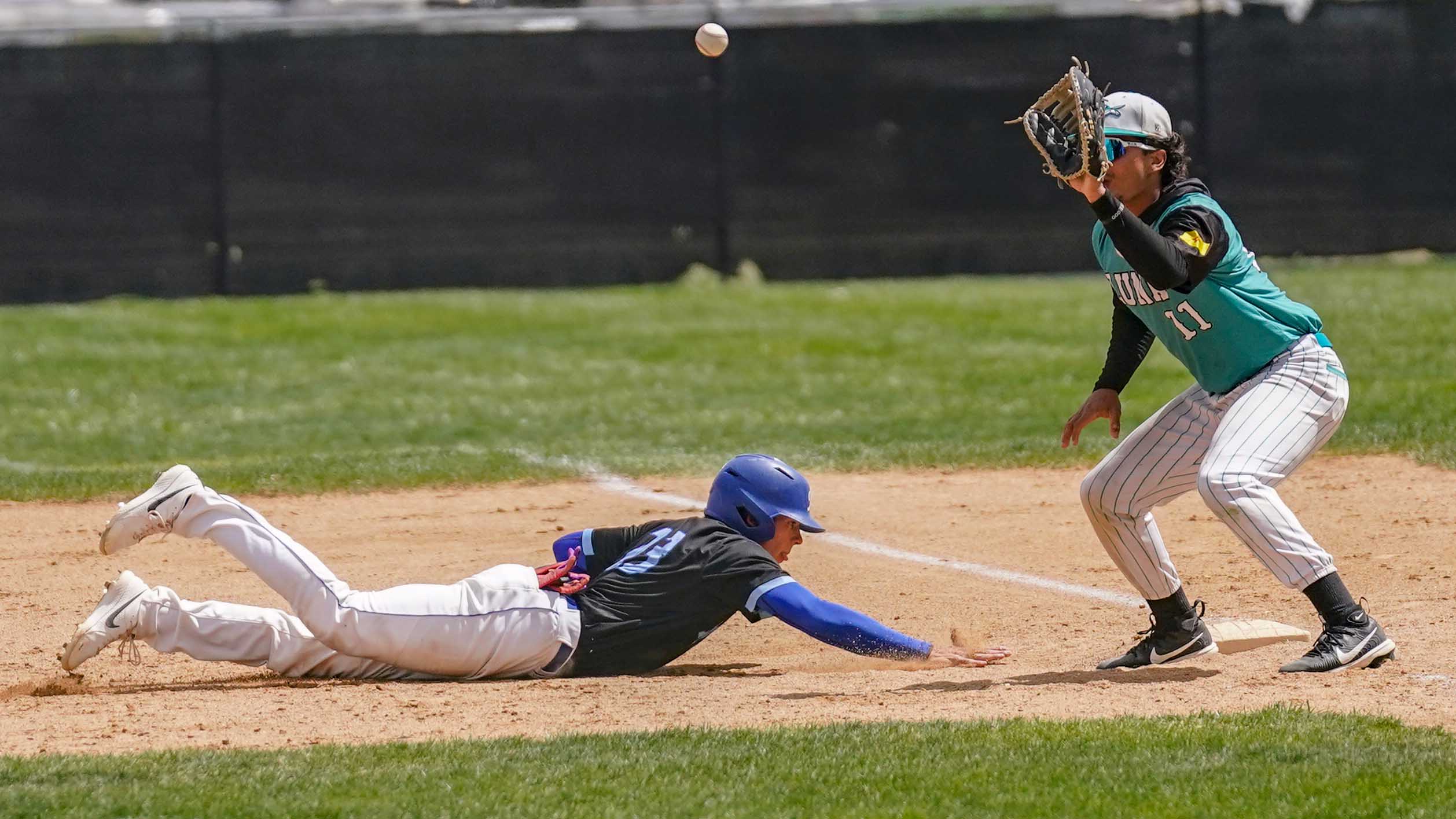 College baseball player diving back to first base after pick-off attempt.