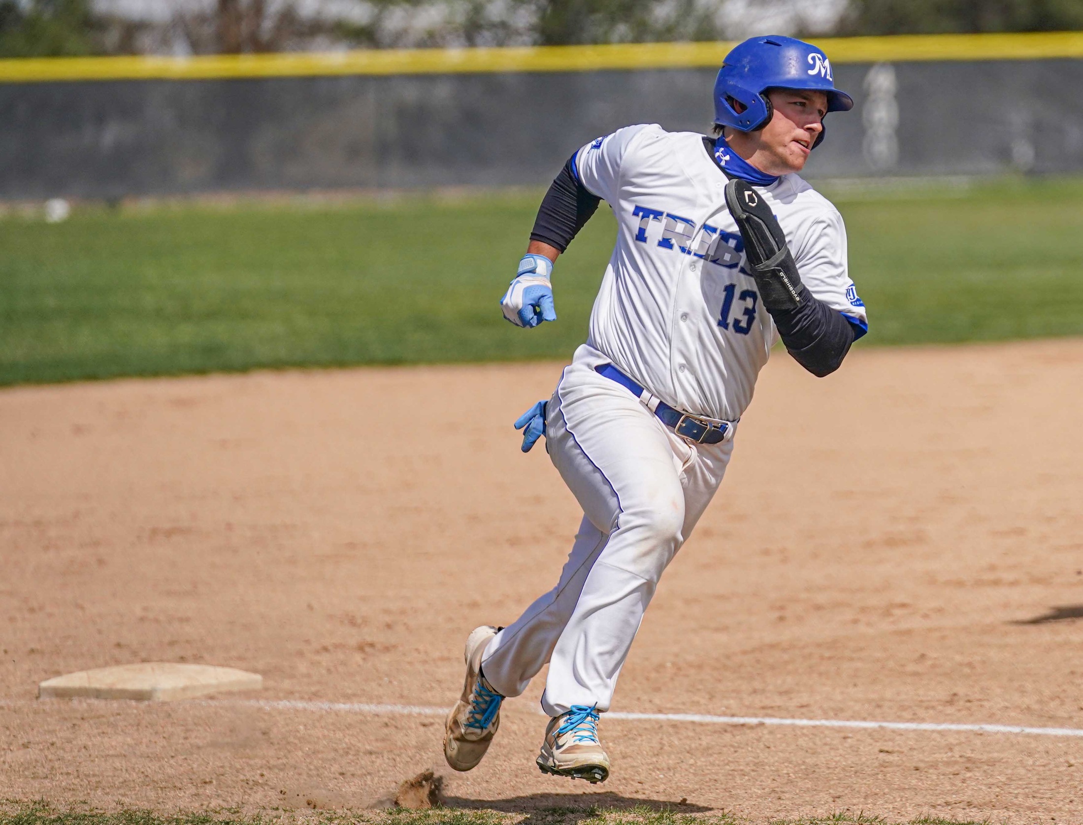 College baseball player rounding third base on the way to score.