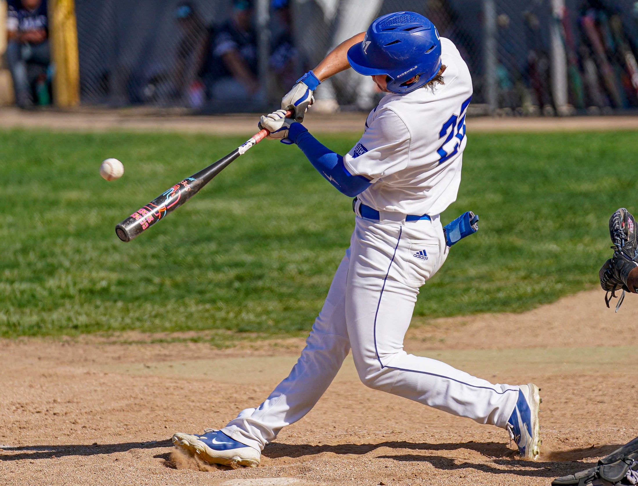 College baseball player hitting the ball.