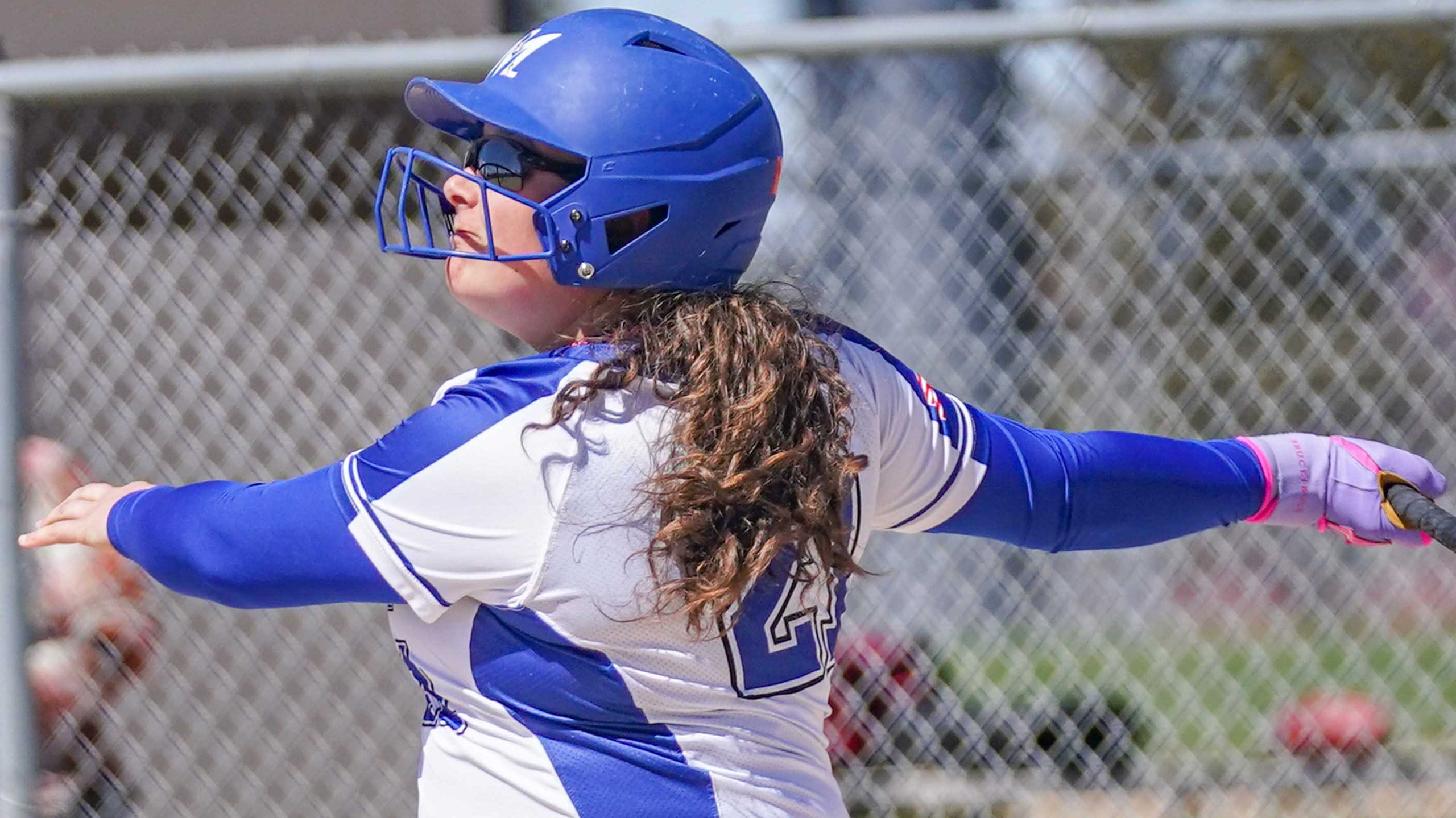 College softball player watches flight of home run ball.