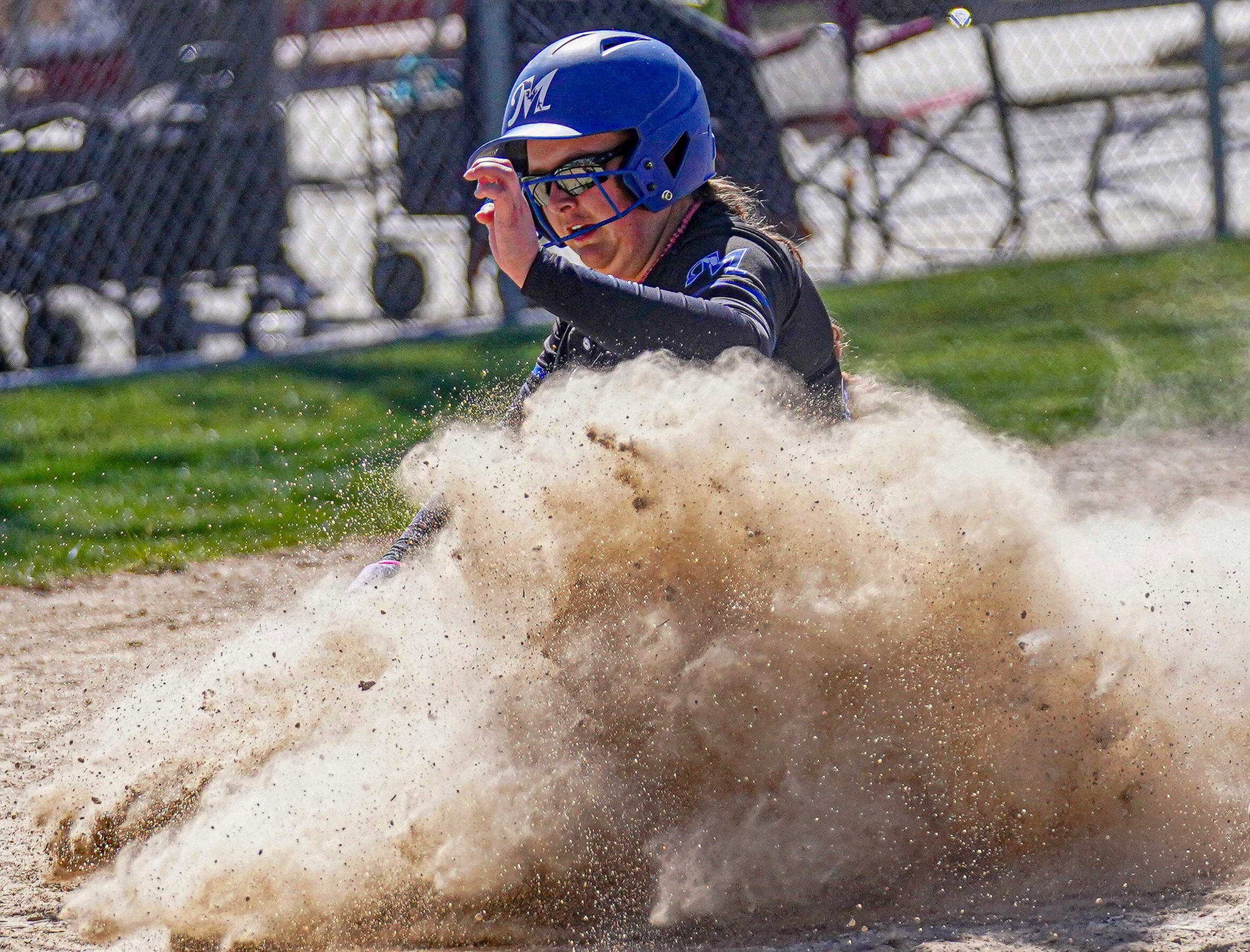 College softball player sliding into home pate.