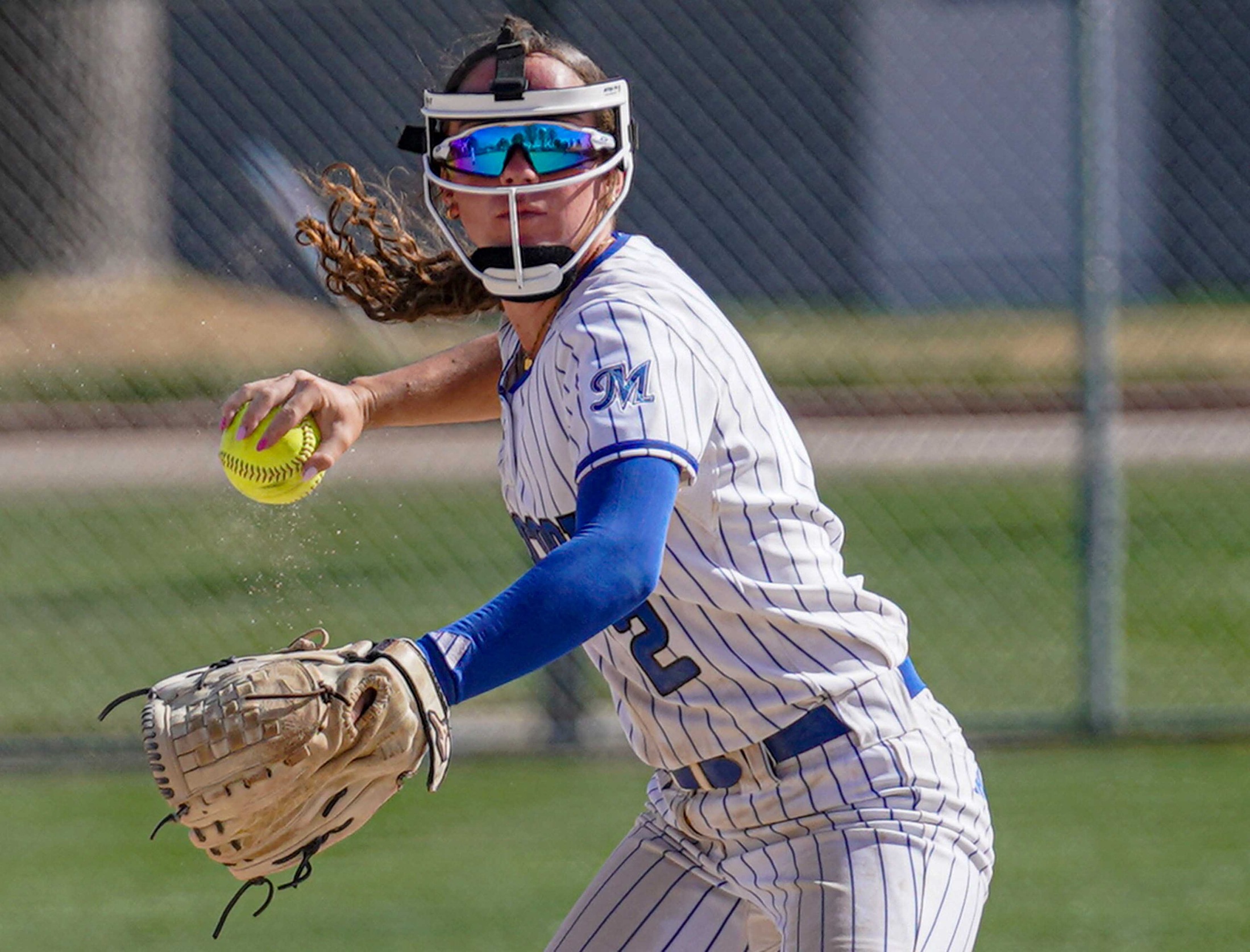 College softball player throwing the ball.