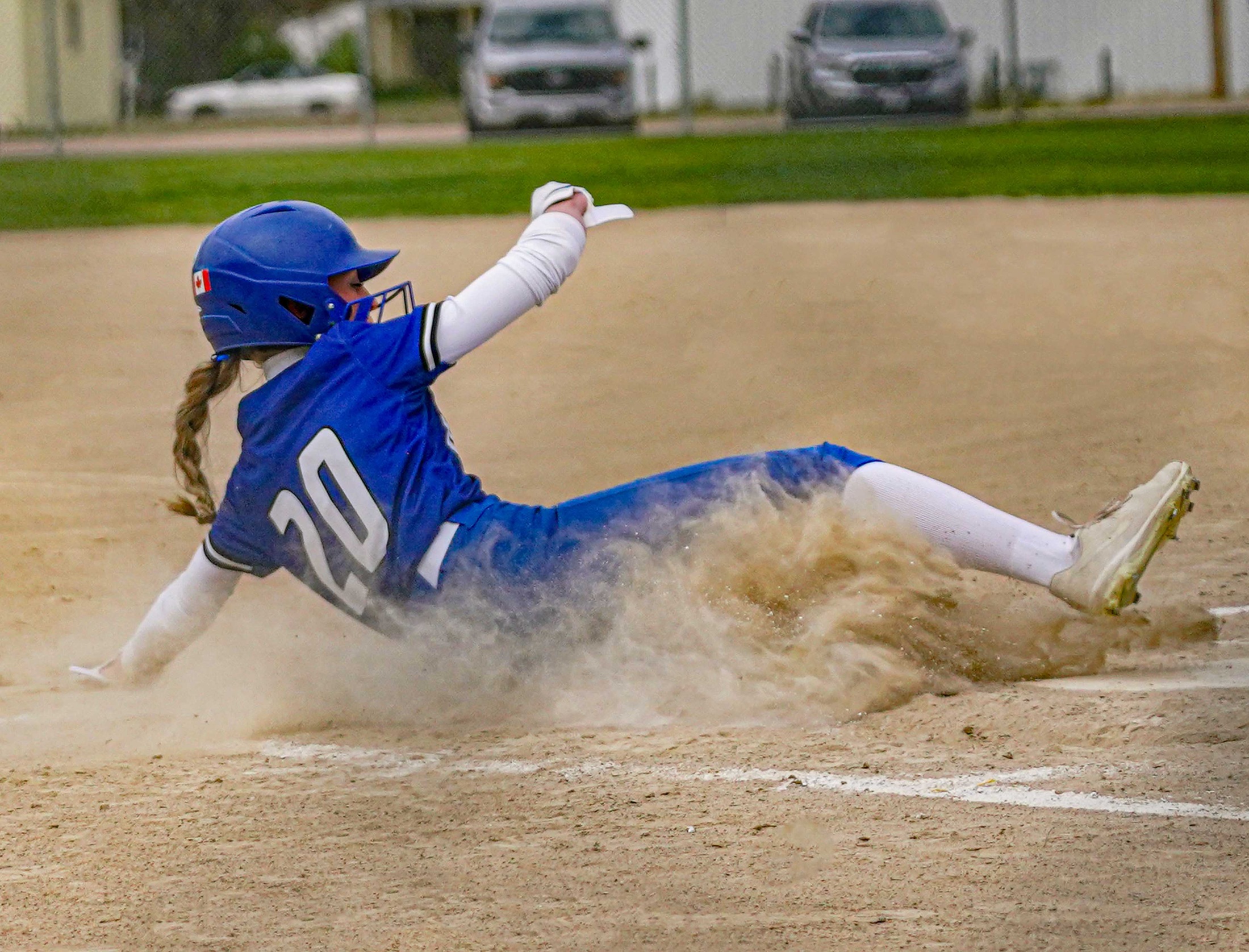 College softball player sliding into home plate.