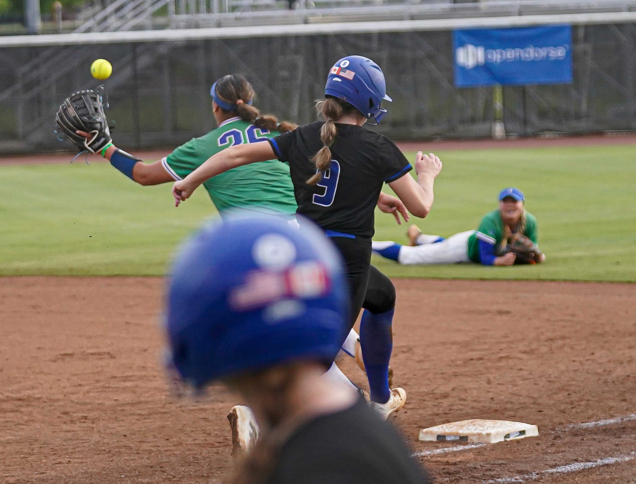 College softball player reaching first base on hit.